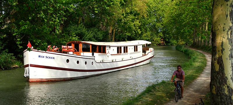 French Hotel Barge Roi Soleil cruising on the canal du midi in the south of france. Go for a bike ride on the towpath